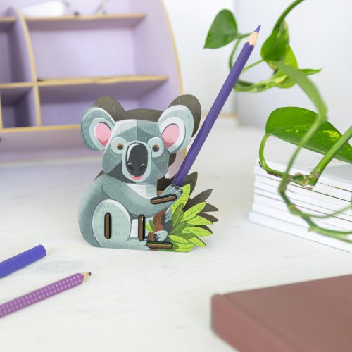 Koala Kalle hält einen Stift griffbereit auf dem Schreibtisch